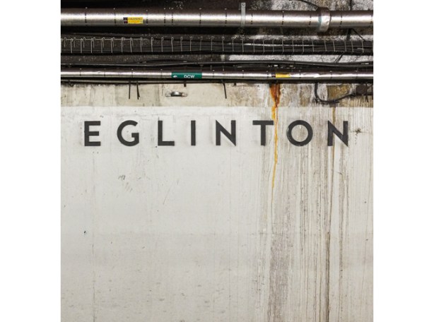 Eglinton sign on walls of subway station where rust from pipes has stained the concrete wall