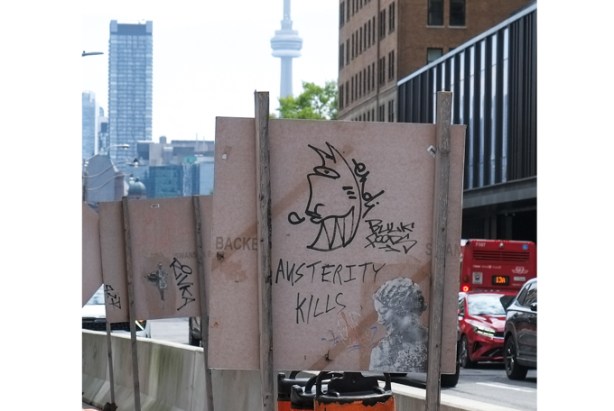 graffiti on the back of a construction sign that says austerity kills