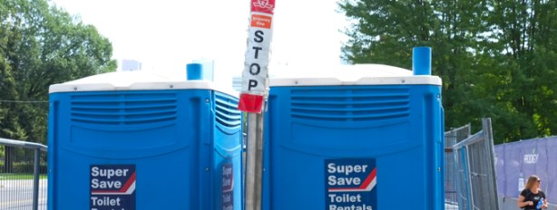 two blue porta potties beside a TTC bus stop sign with a temporary stop sign on it. At entrance to museum subway station