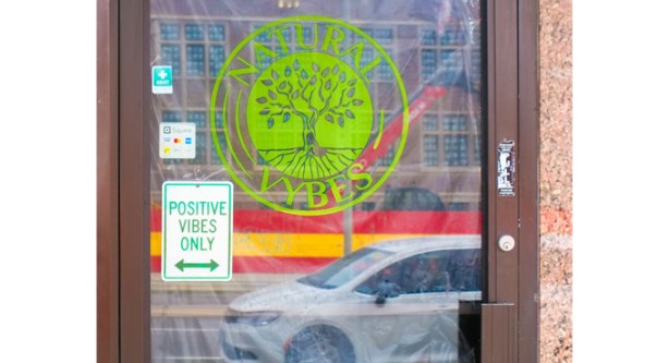 glass door on store has circular green sign with picture of a tree and words saying natural vybes