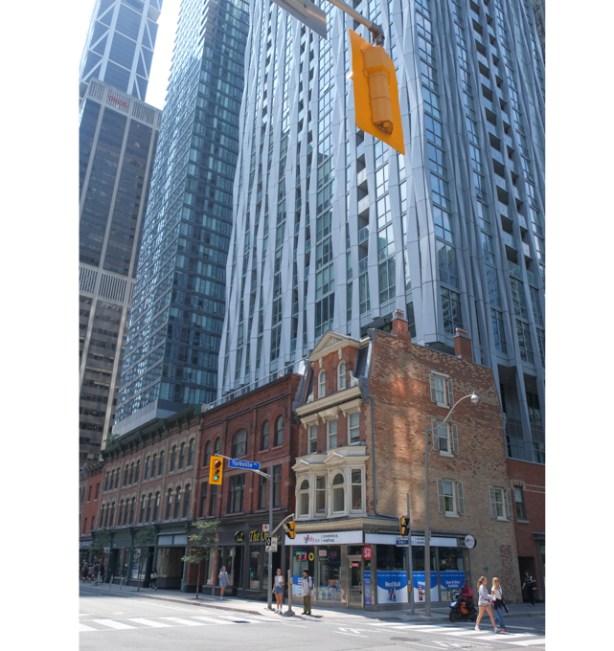 southwest corner of Yonge and Yorkville, older brick buildings at street level, tall glass and steel condos rising behind them