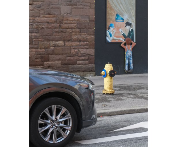 car parked in front of building where fake window with a painting of a young boy looking into the window of a restaurant