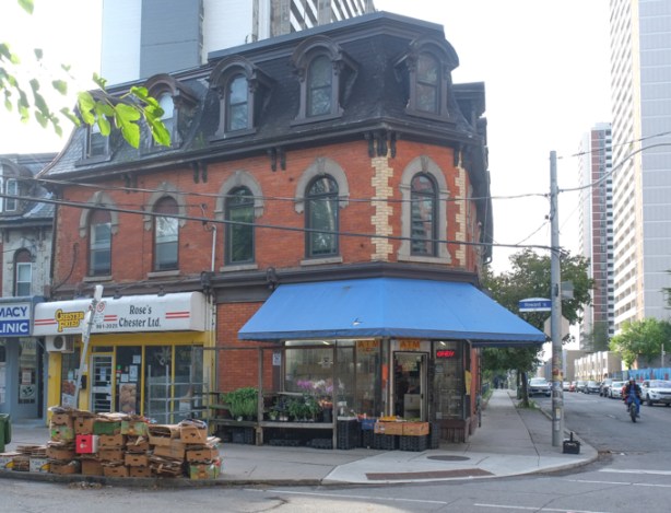 old brick building, second empire style, with black roof, large blue awning over front door,