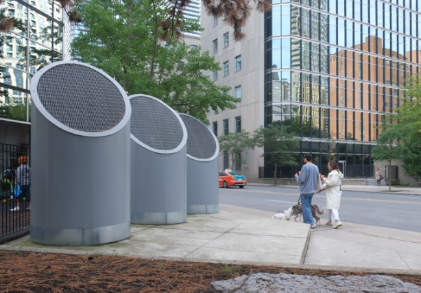 large grey ventilation shafts rising from the sidewalk behind 160 Bloor East, people walking past