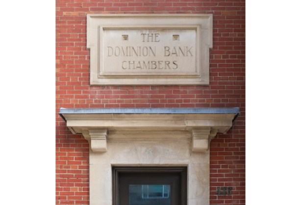 doorway in red brick bank building with sign over door carved stone, that says The Dominion Bank Chambers