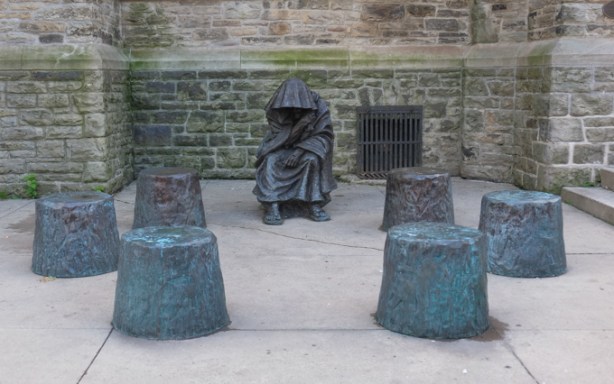 sculpture of homeless person begging, covered in hooded robe