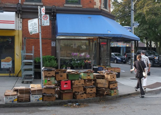 empty cardboard boxes stacked up on the sidewalk outside of a store, waiting for garbage or recycling collection
