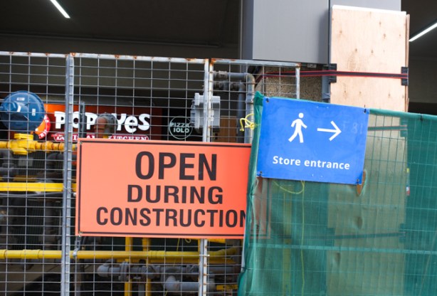 sign that syas stores open during construction, mounted on hoardings