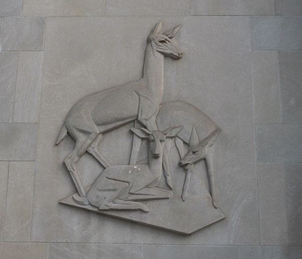 stone relief sculptures on side of building, deer family