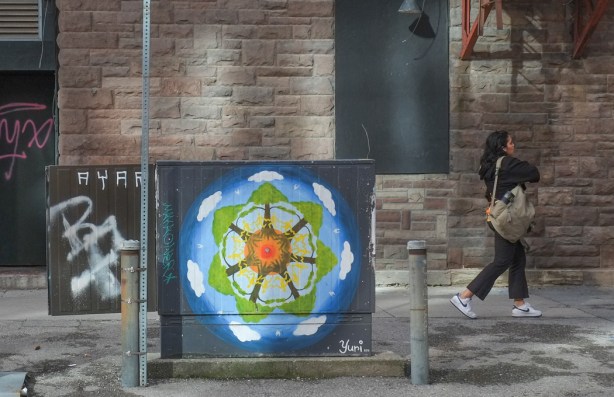 woman walking past a sidewalk box that has been painted